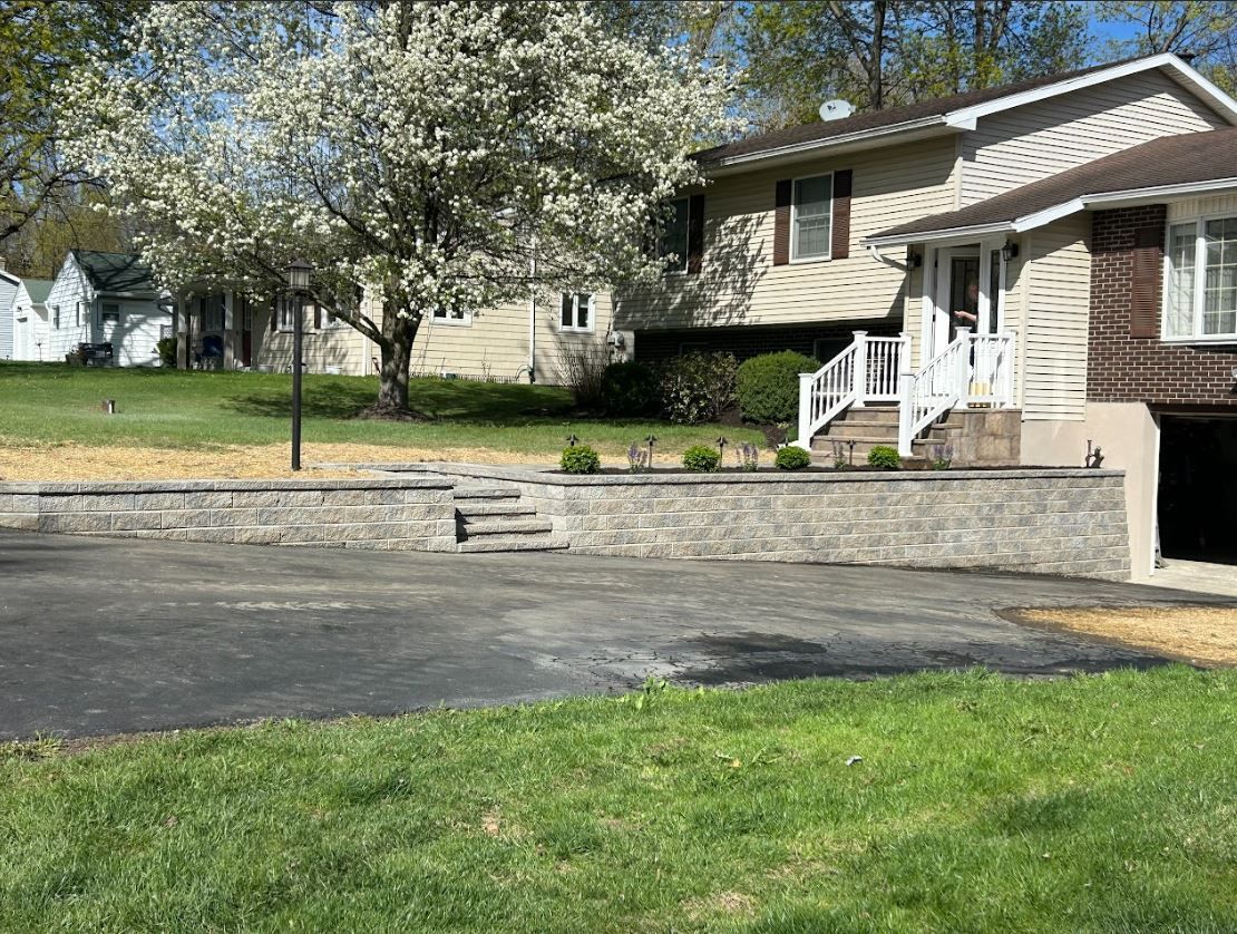 A house with a stone wall and stairs in front of it.
