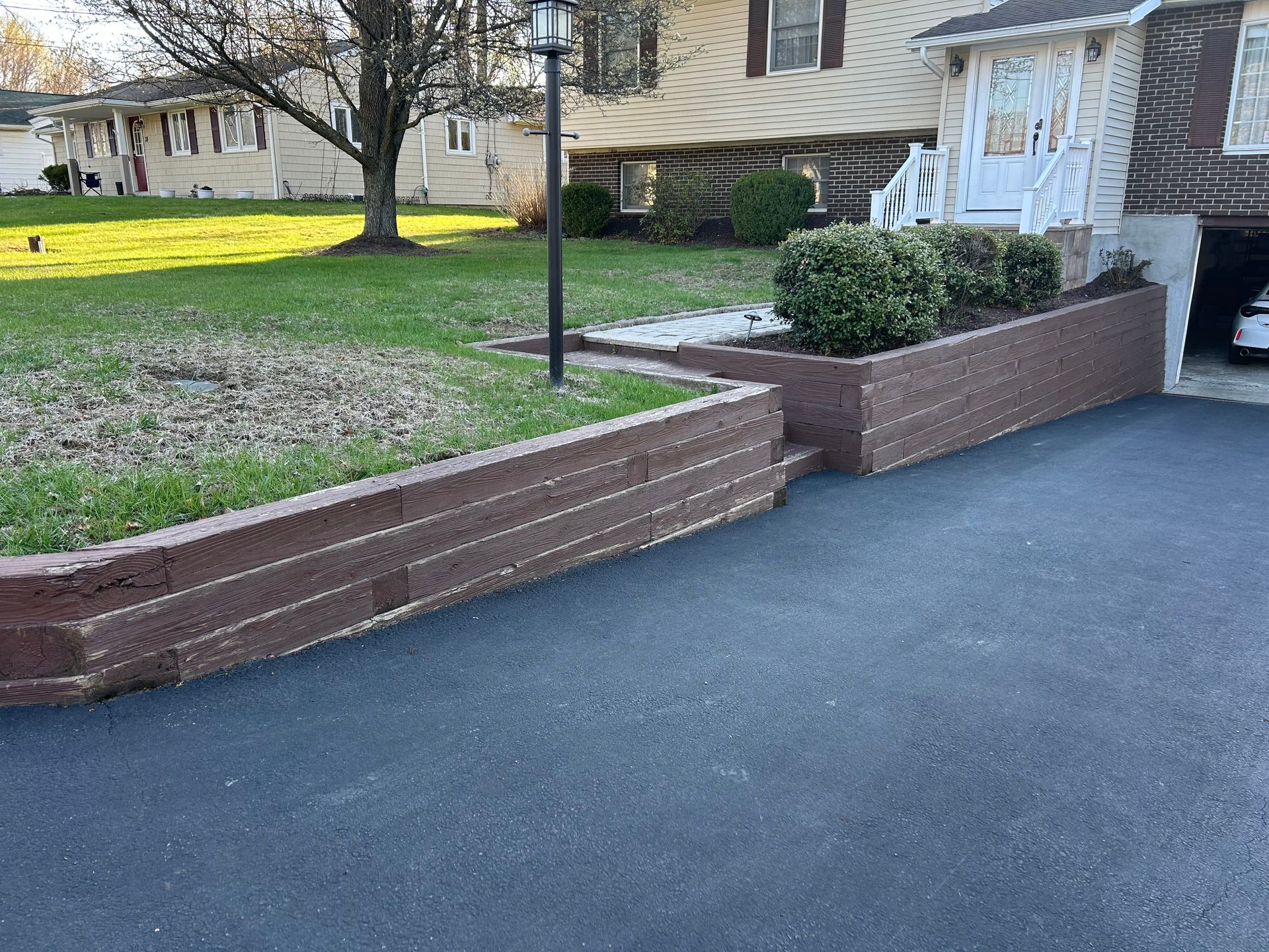 A car is parked in a driveway next to a brick wall.