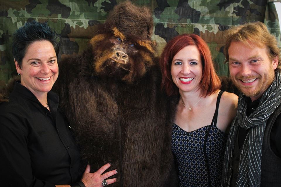 A group of people are posing for a picture with a stuffed animal.