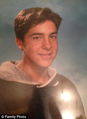 A young man in a hoodie is smiling for a picture.