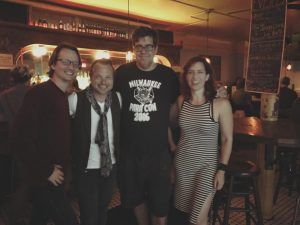 A man in a milwaukee shirt is posing for a picture with two other people
