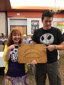 A man and a woman are holding a wooden board in a room.