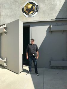 A man is standing in front of a large door.