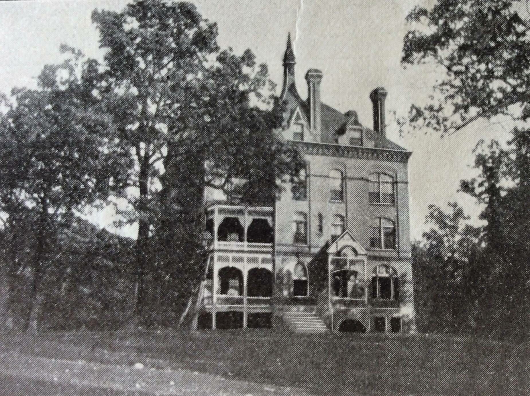 A black and white photo of a large building surrounded by trees