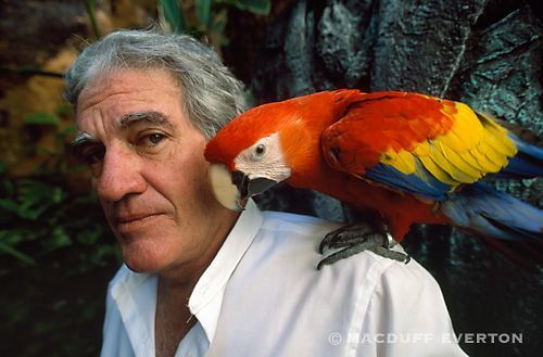 A man with a colorful parrot on his shoulder