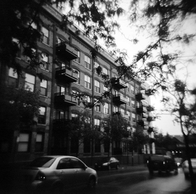 A black and white photo of a building with cars parked in front of it