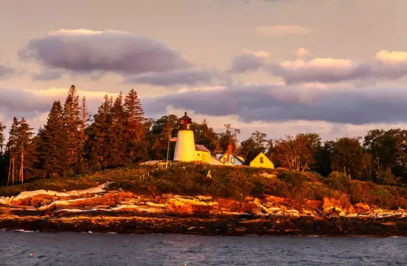 A lighthouse is sitting on top of a small island in the middle of the ocean.