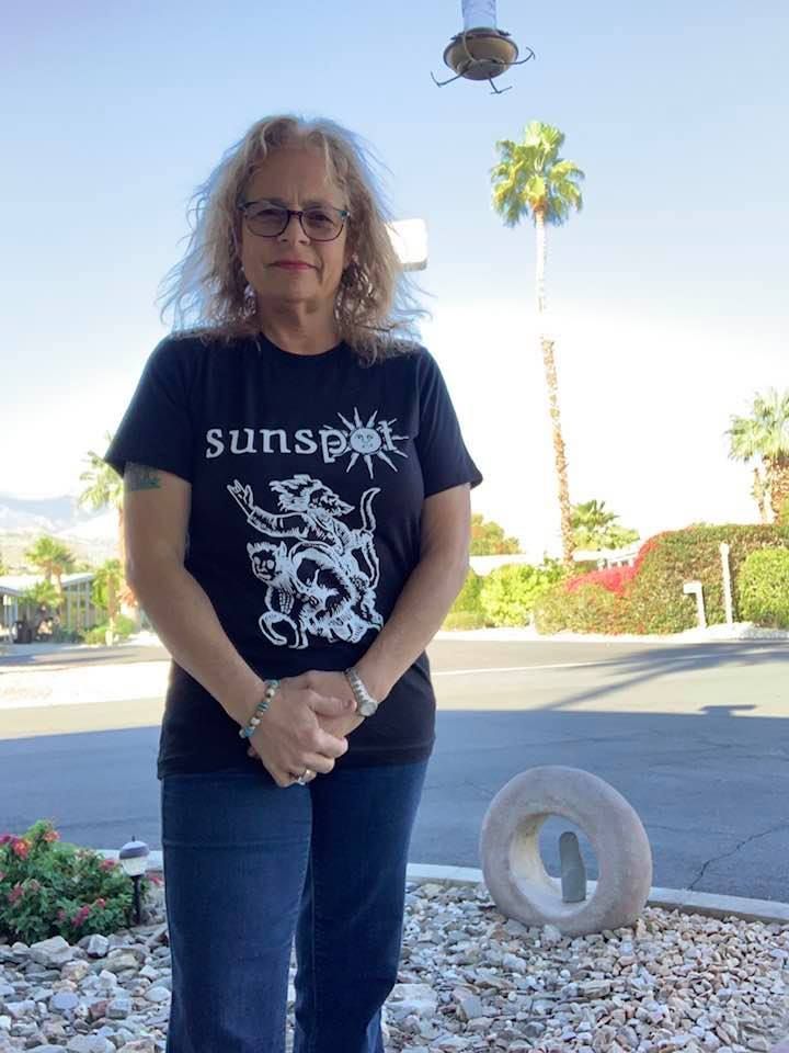 A woman wearing a black shirt with the word sunset on it