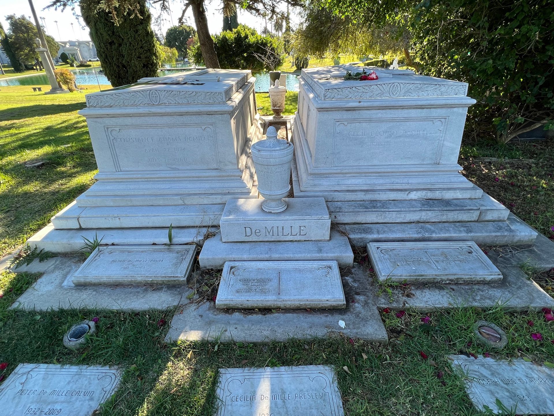 A couple of graves in a cemetery with a vase on top of them.