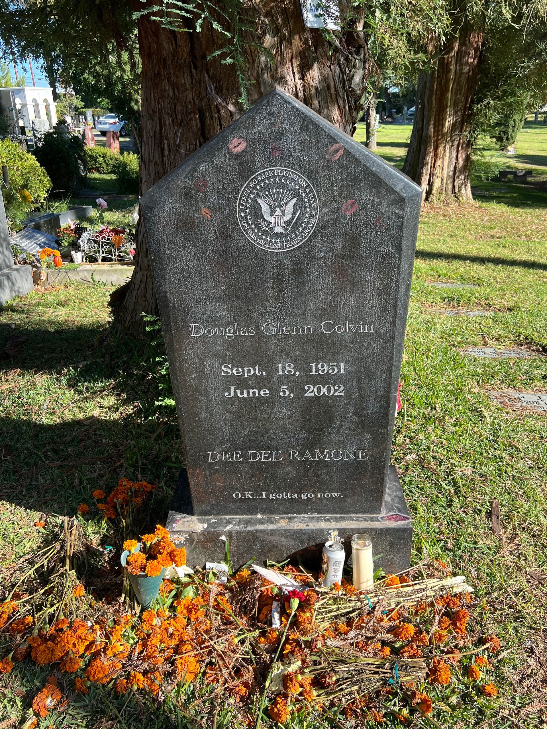 A gravestone in a cemetery surrounded by flowers and candles.