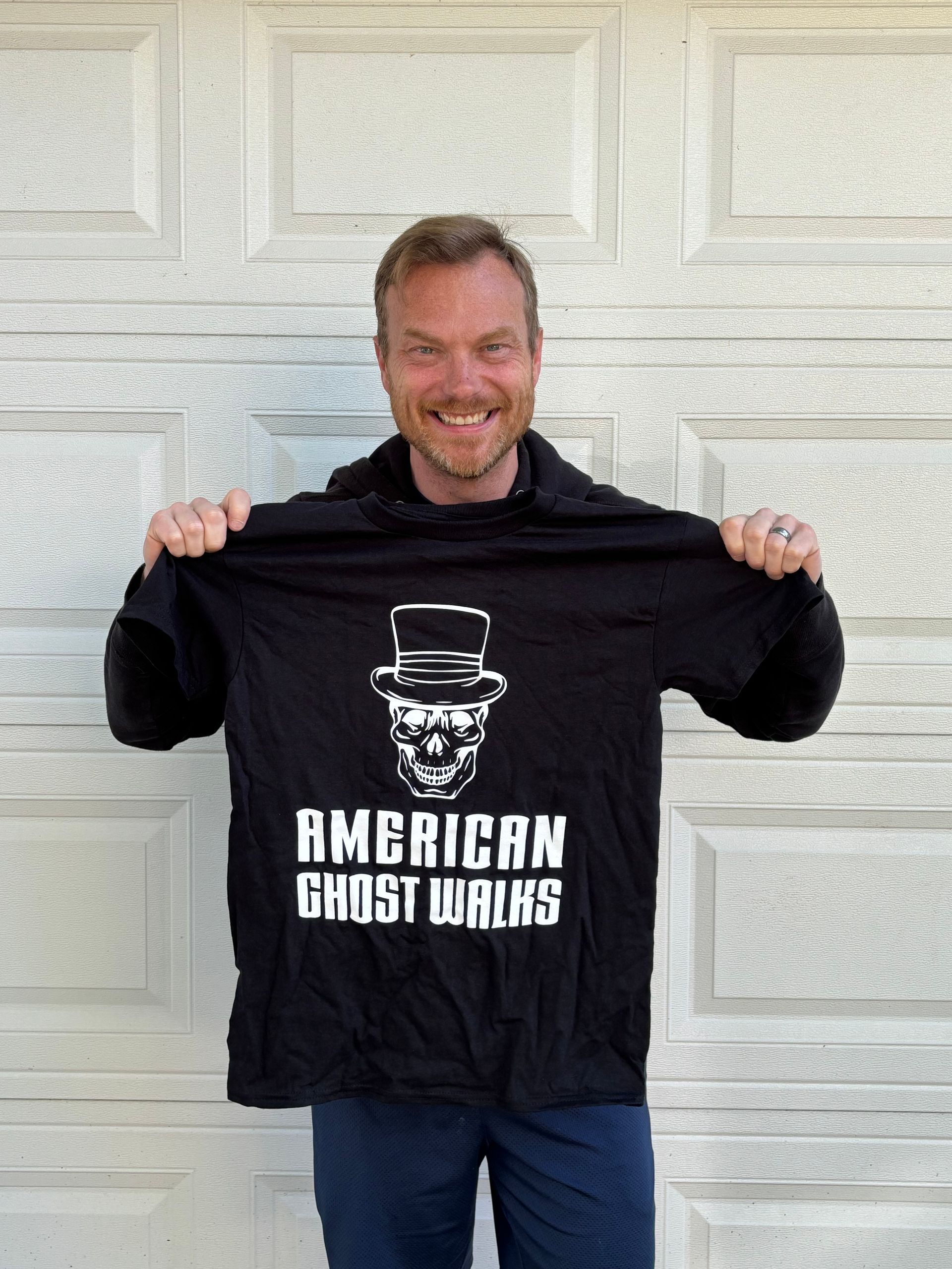 Mike Huberty holding an American Ghost Walks t-shirt