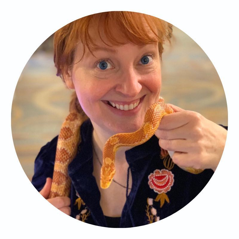 A woman is smiling while holding a snake around her neck