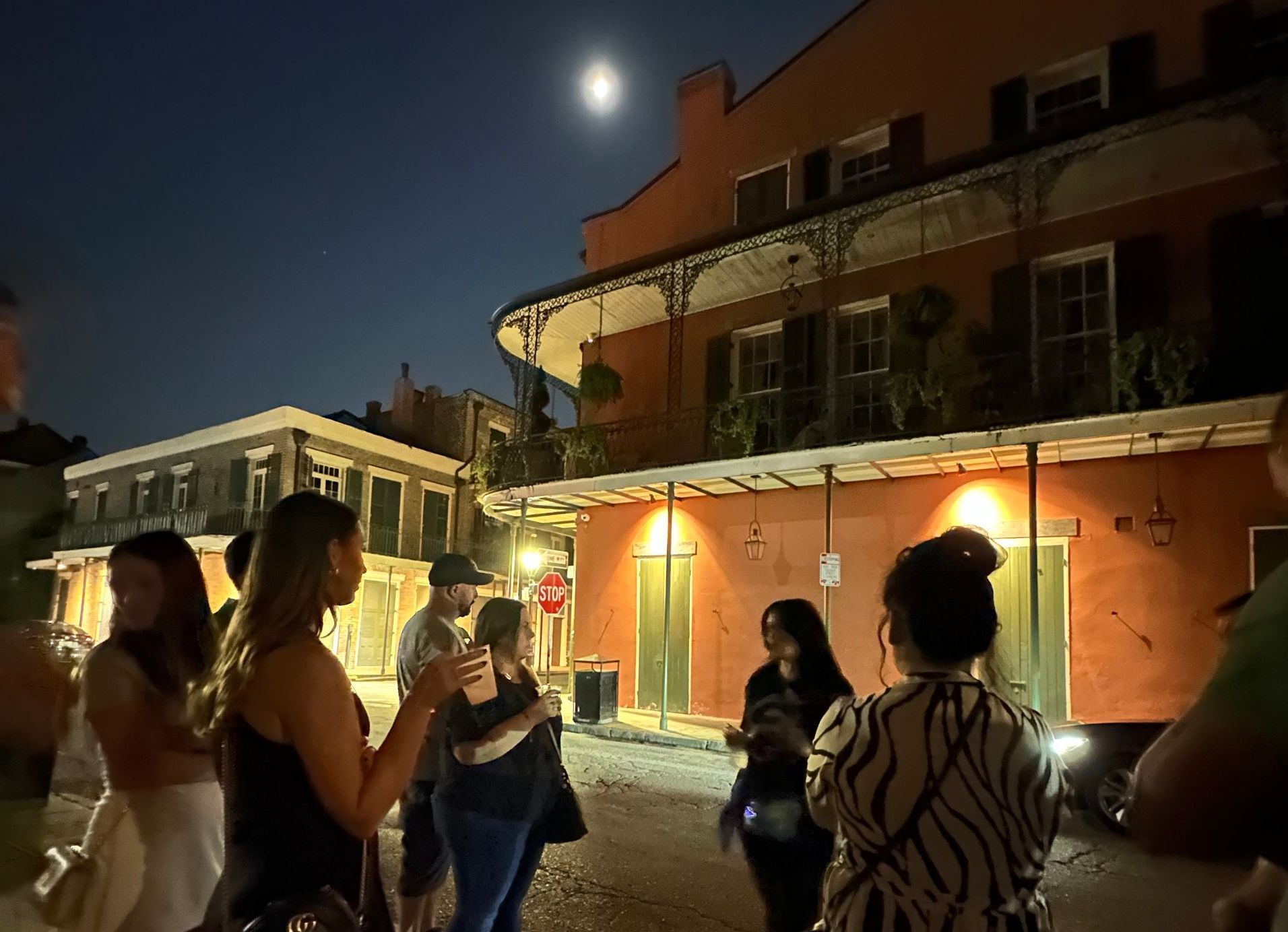 People listen to a guide telling a story on a dark street