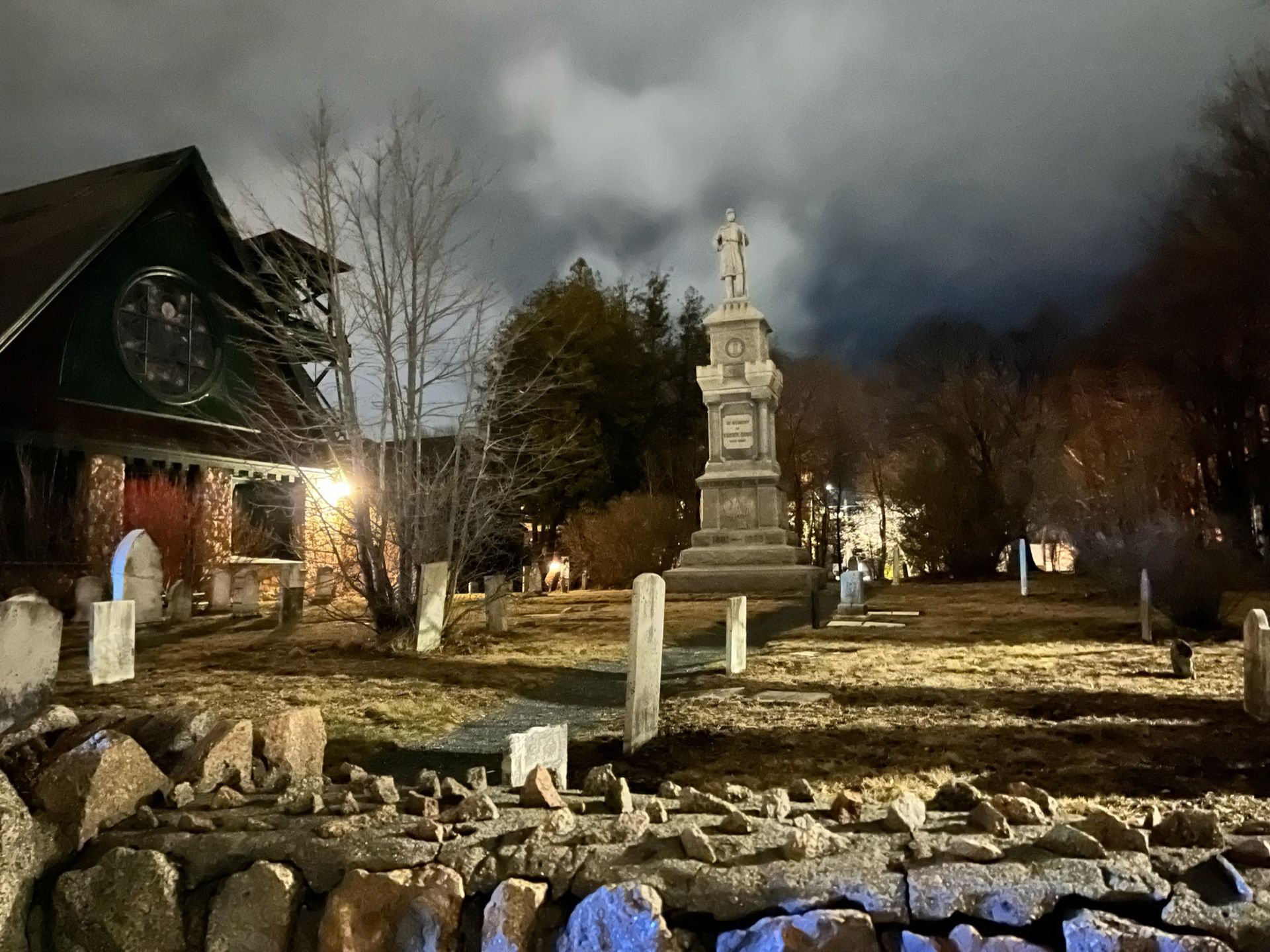 A cemetery at night with a house in the background