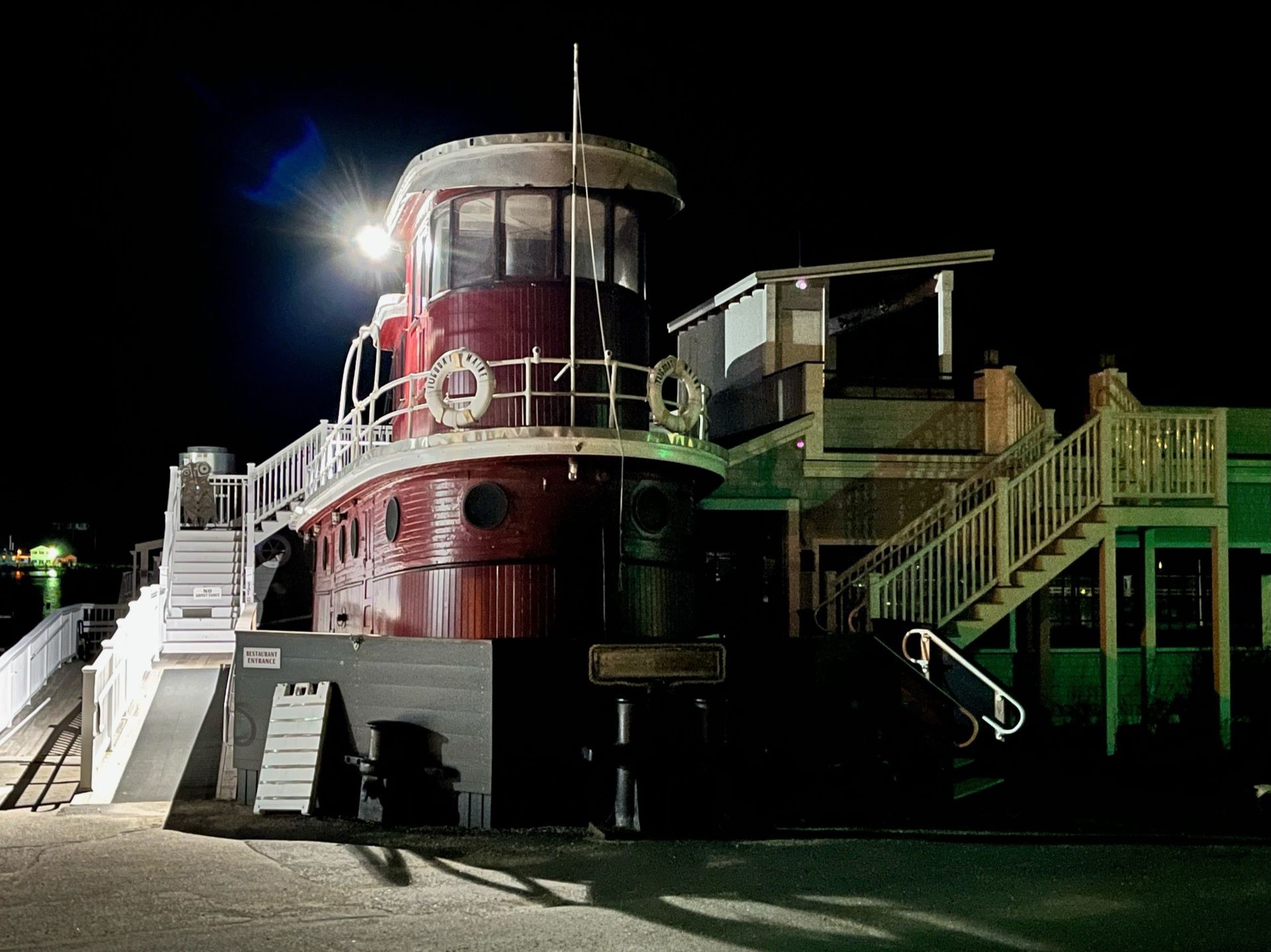 A large red boat with stairs leading up to it is lit up at night