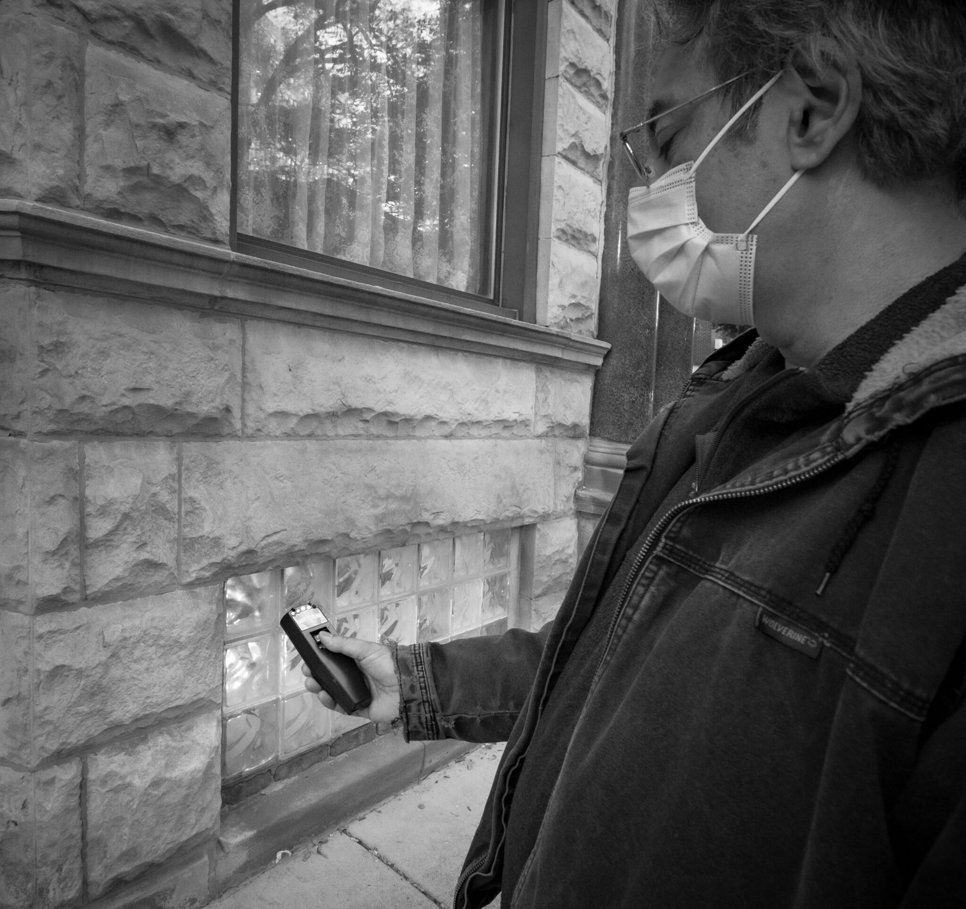 A man wearing a mask is looking at a cell phone