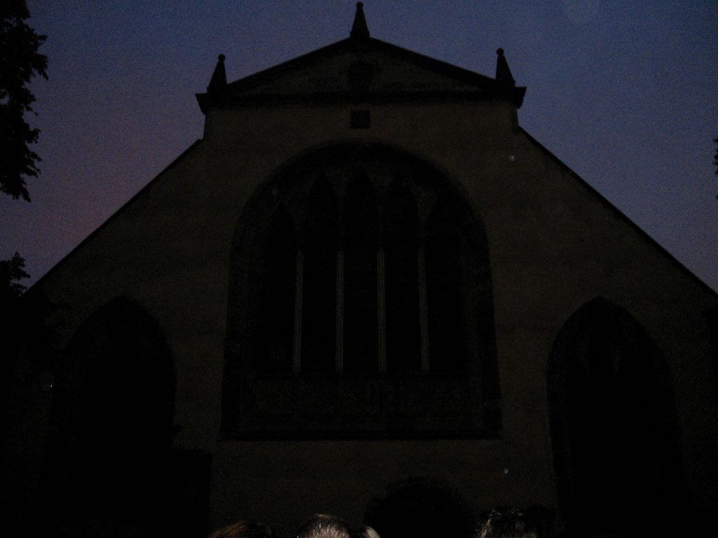 A group of people standing in front of a church at night