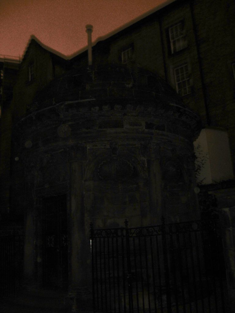 A dark building with a fence in front of it at night.