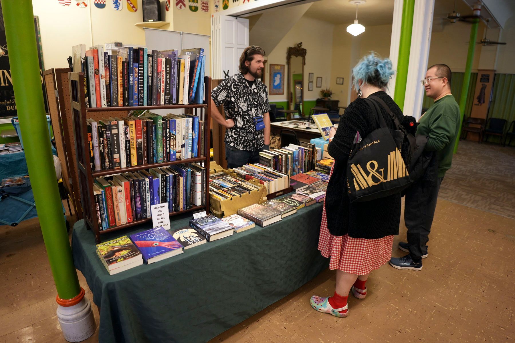 A woman with blue hair is looking at books on a table