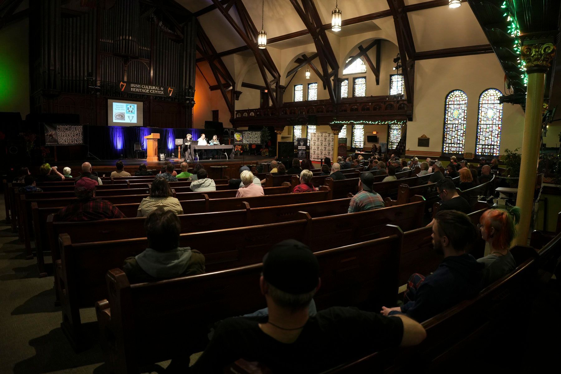 People are sitting in a church with stained glass windows
