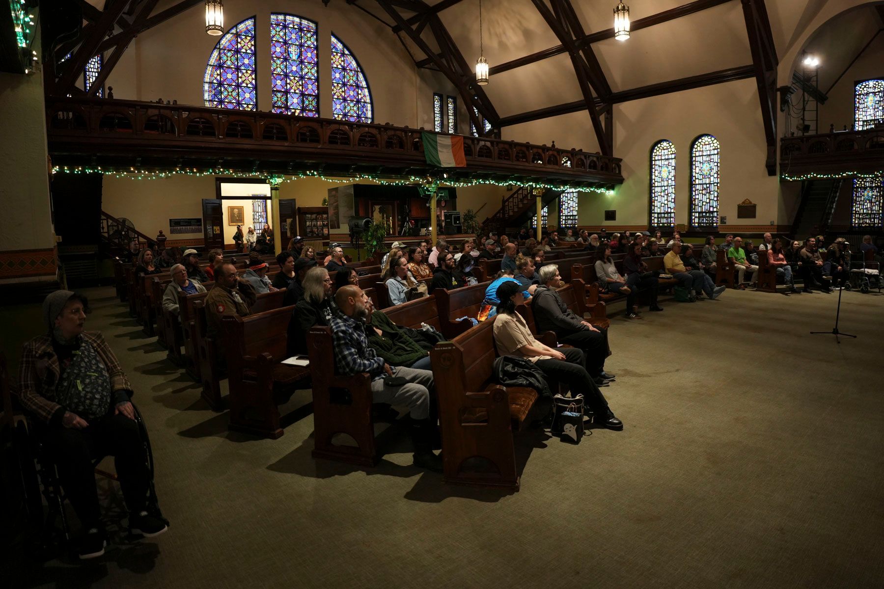 A large group of people are sitting in a church with stained glass windows