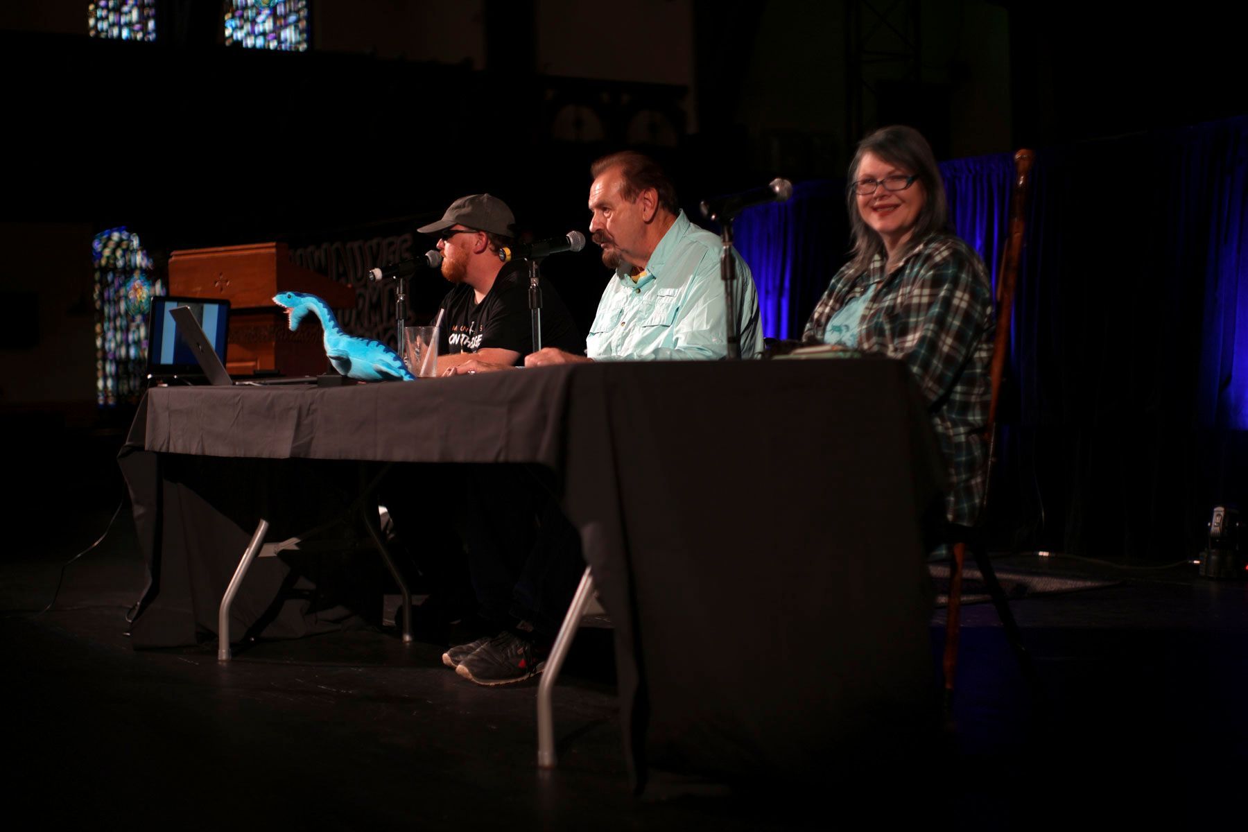 Three people sit at a table in a dark room