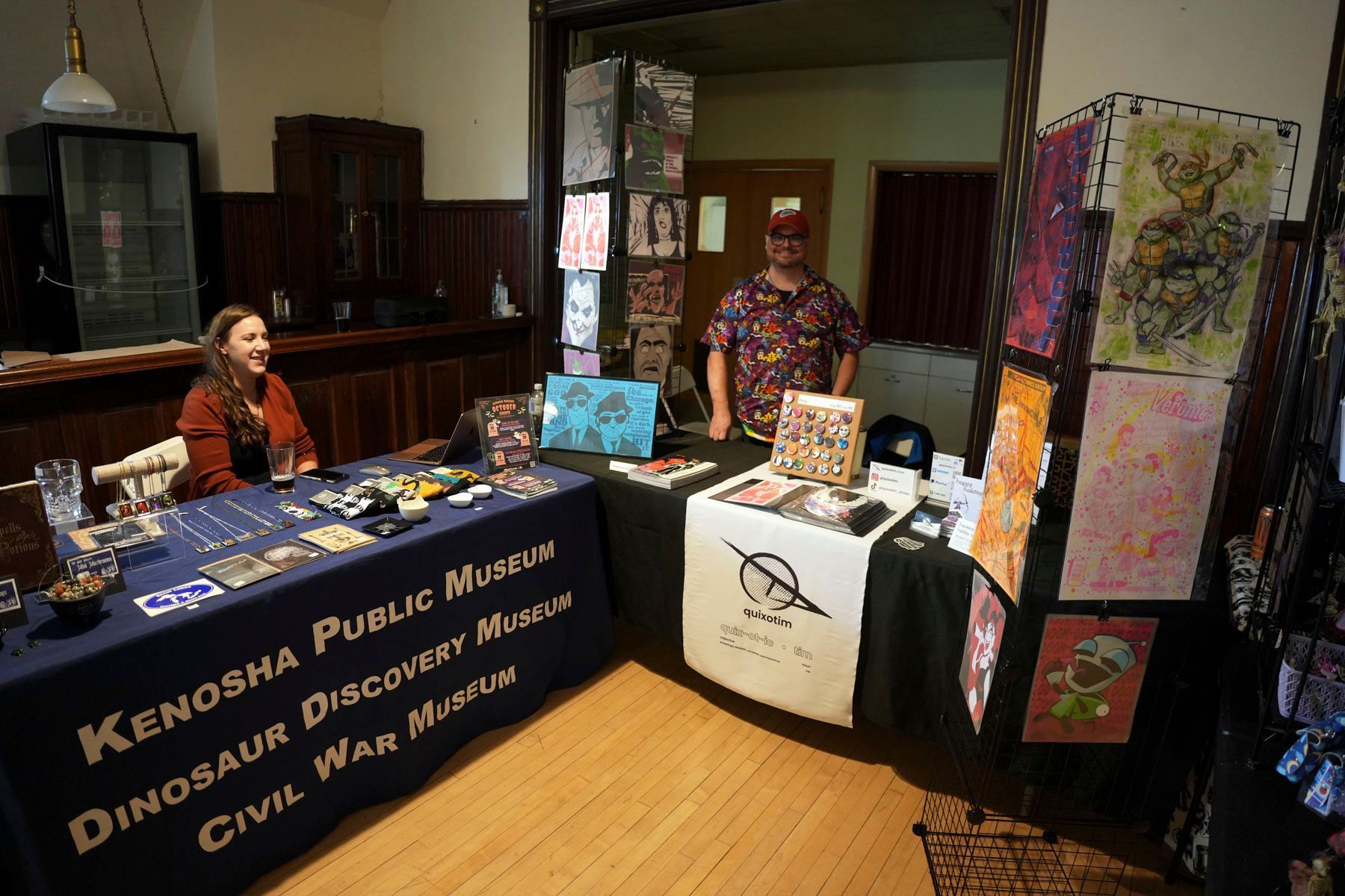 A woman sits at a table with kenosha public museum written on it