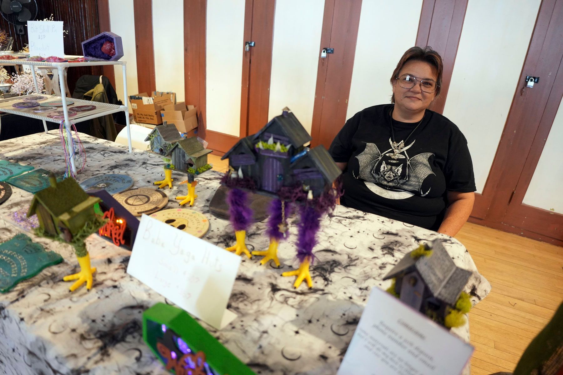A woman sits at a table with a display of houses and chickens