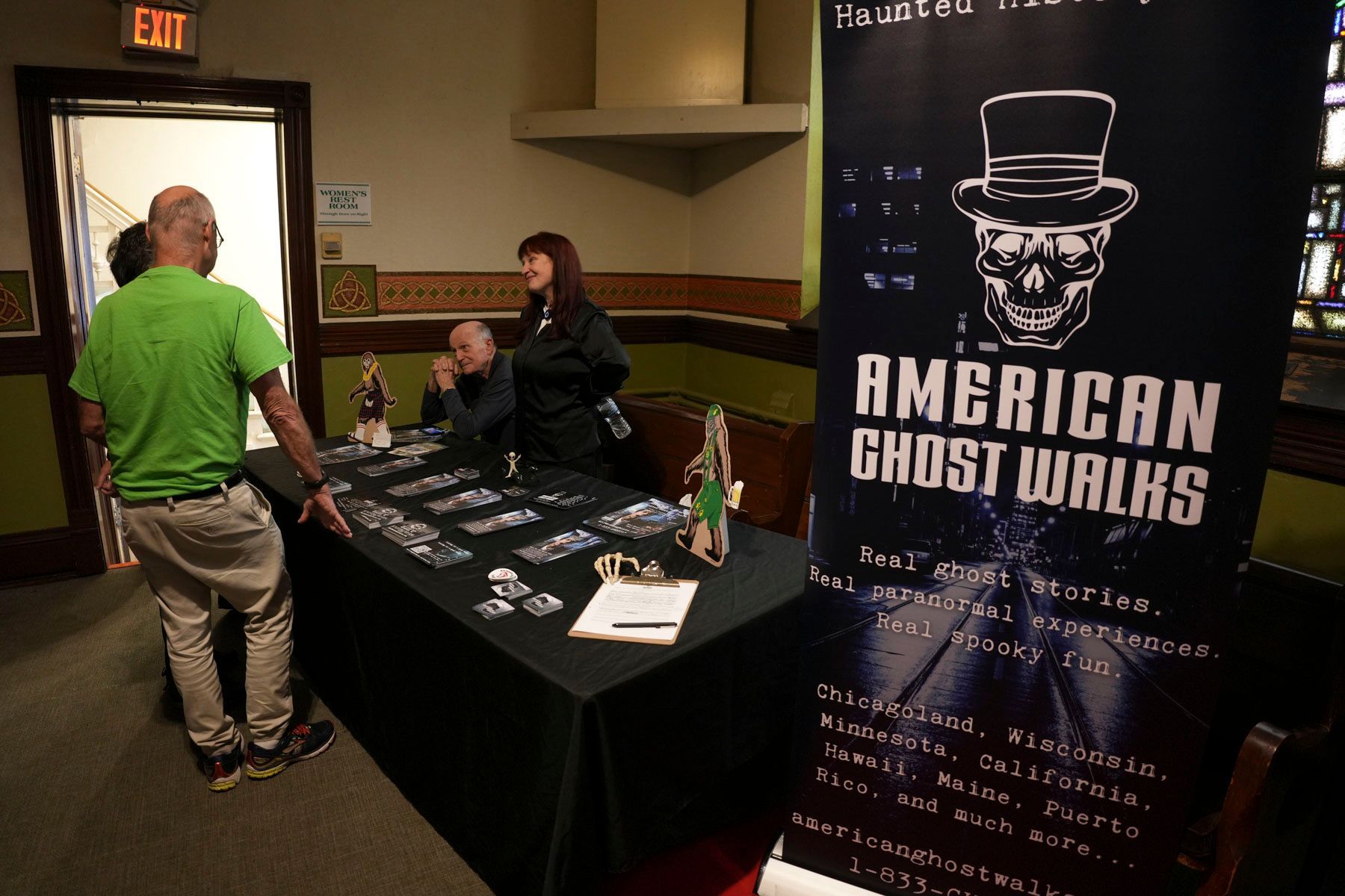 People standing around a table with a sign that says american ghost walks