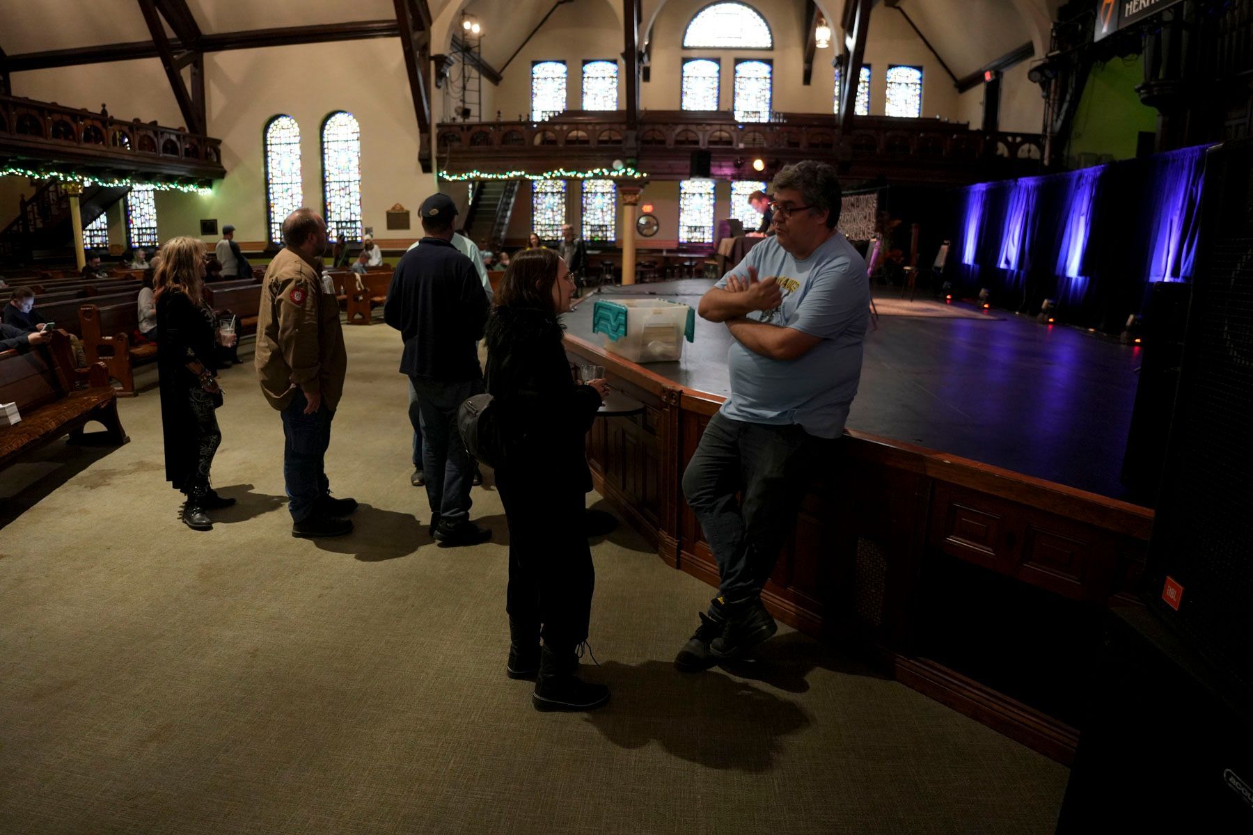 A man in a blue shirt sits on a counter in a church