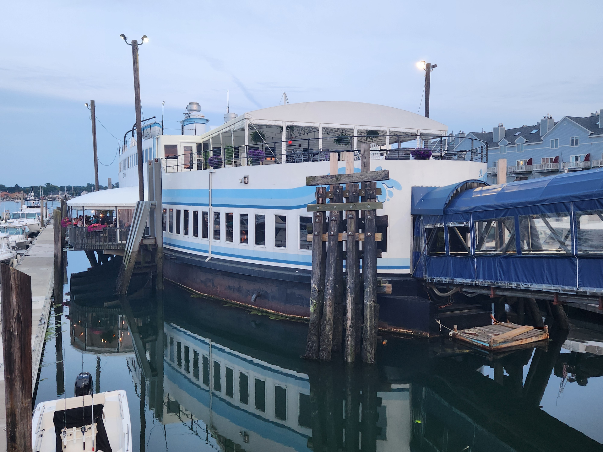 A white and blue boat is docked at a dock