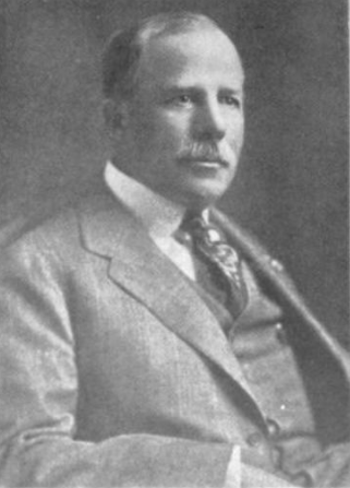 A black and white photo of a man in a suit and tie