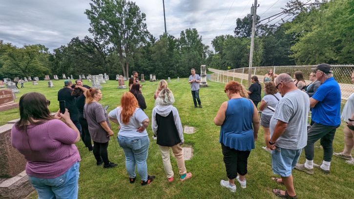 A group of people in a cemetery listens to a tour guide