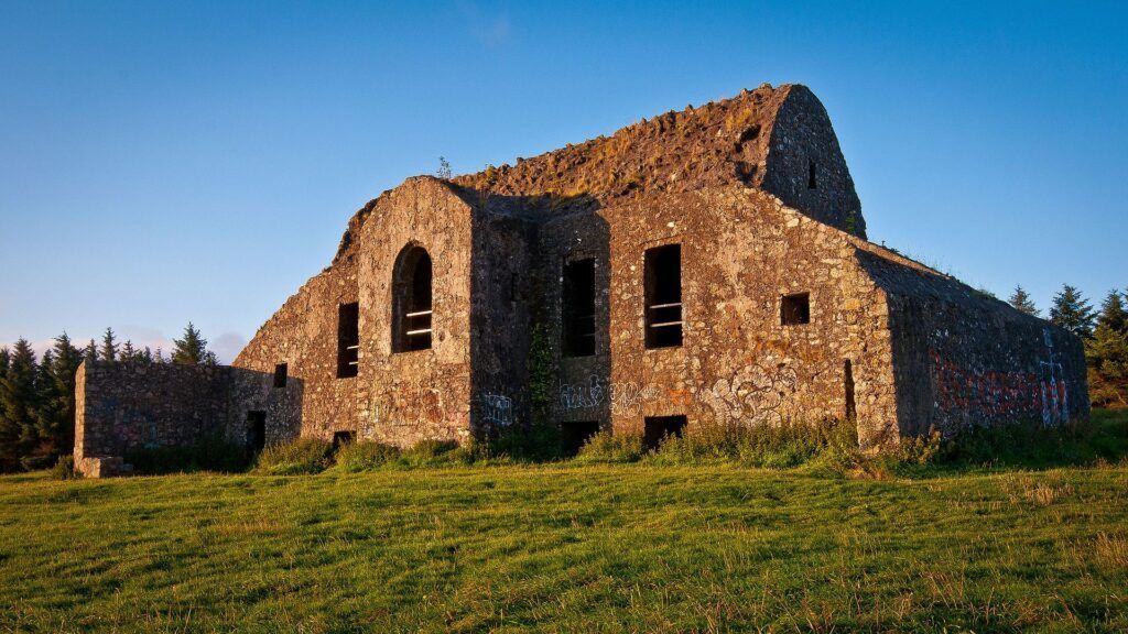 A large stone building is sitting in the middle of a grassy field.