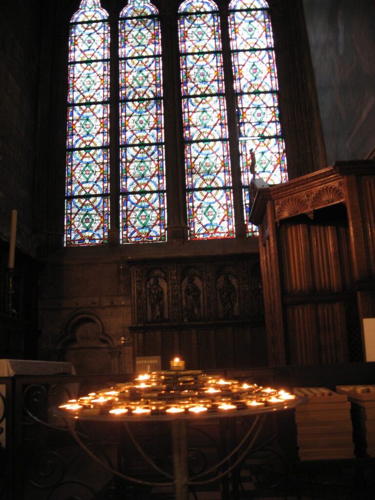 A table with candles in front of a stained glass window