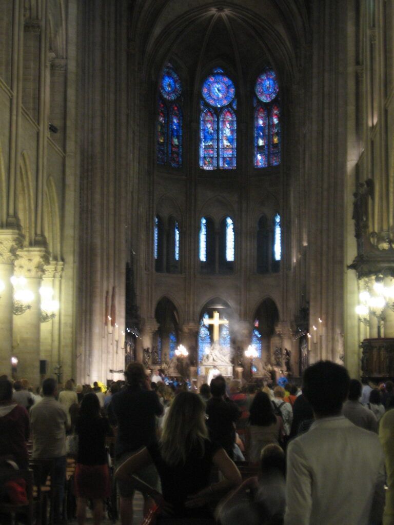 A crowd of people are gathered in a church with stained glass windows