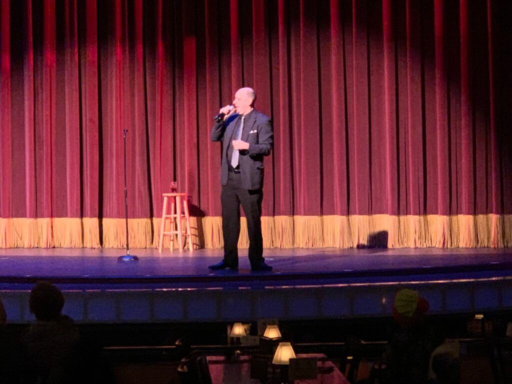 A man is standing on a stage holding a microphone.