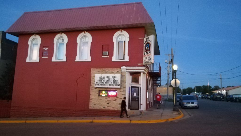 A man is walking in front of a red building