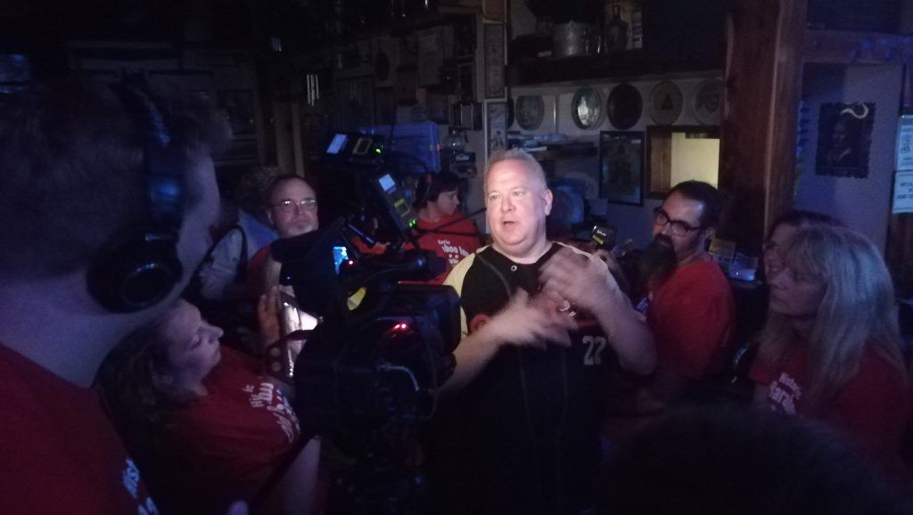 A man wearing headphones is talking to a group of people in a dark room.