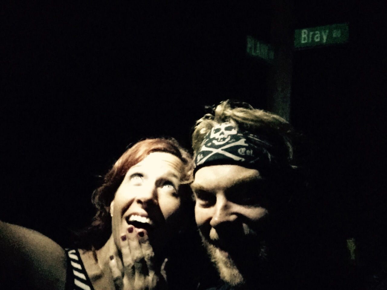 A man and a woman are posing for a picture in the dark.