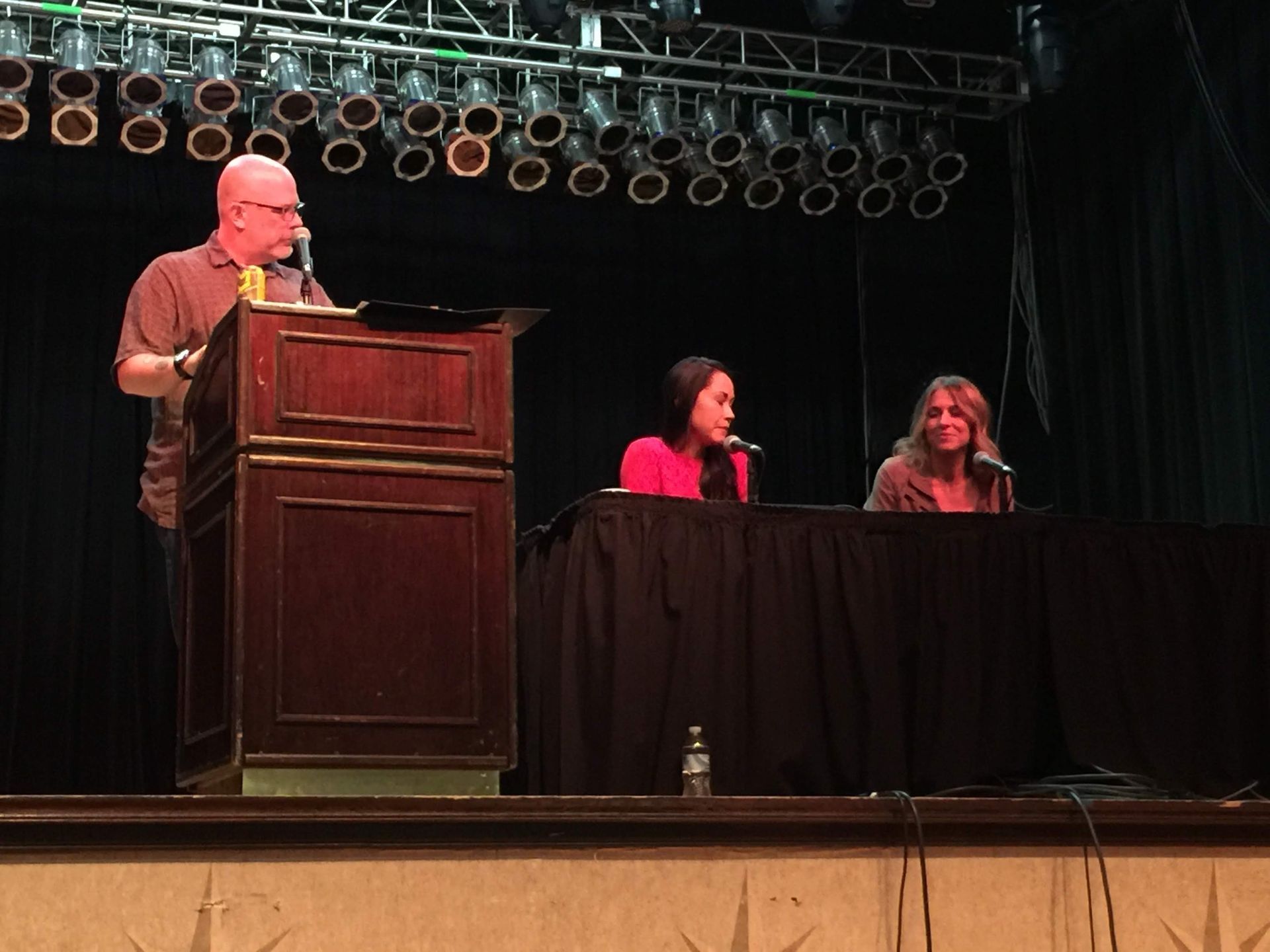 A man stands at a podium with two women behind him