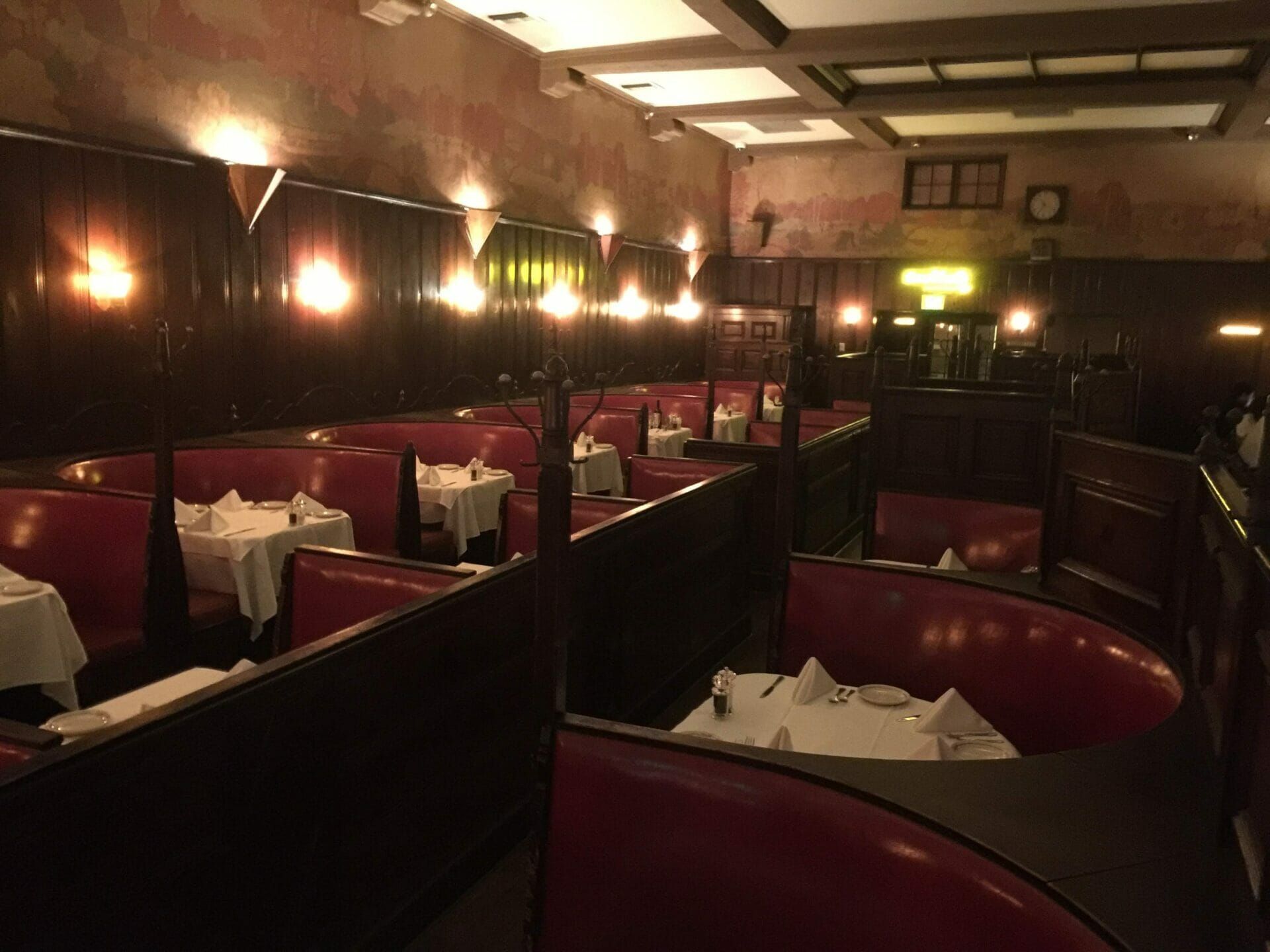 The inside of a restaurant with red booths and tables