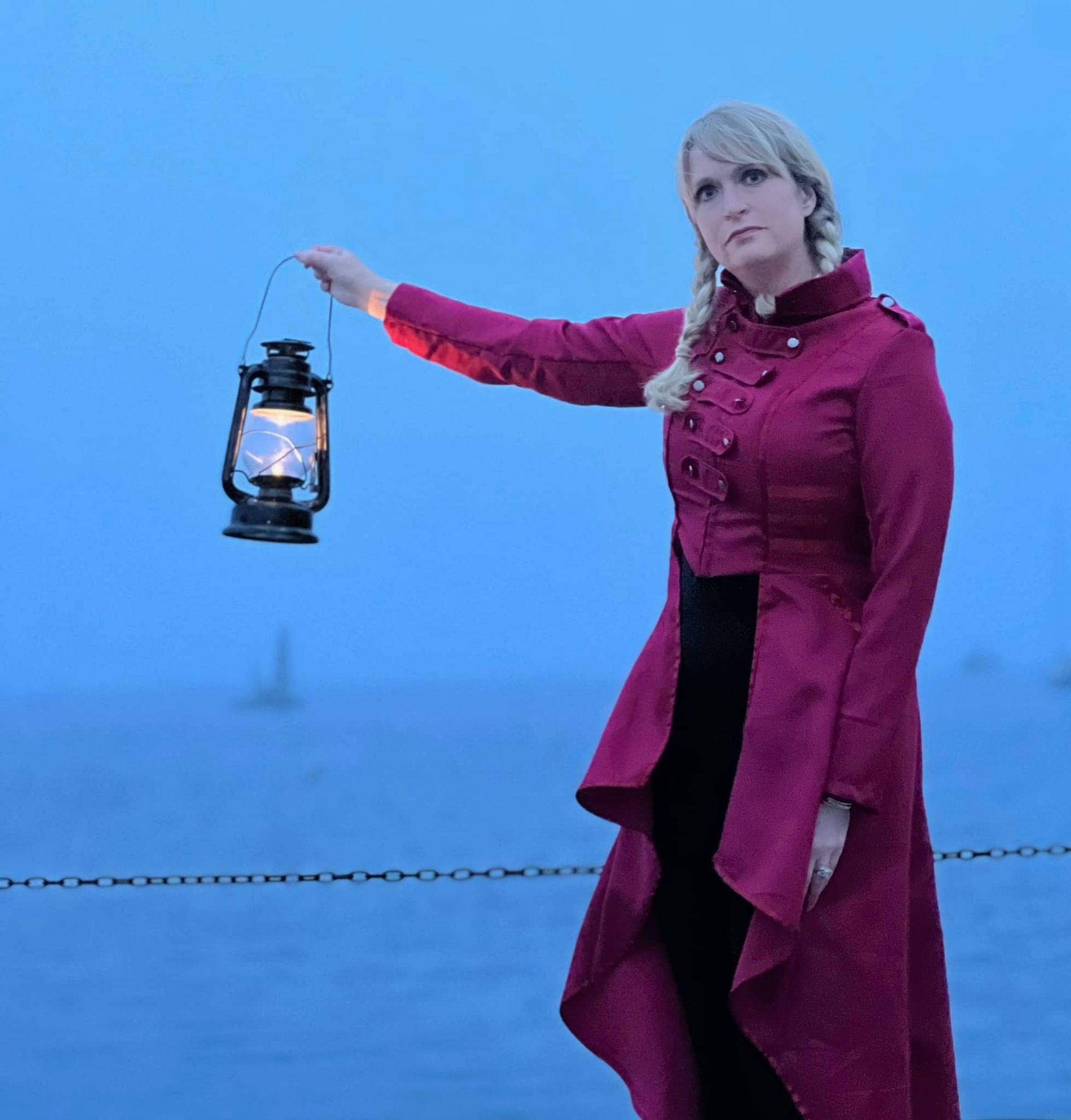 A woman in a pink coat is holding a lantern