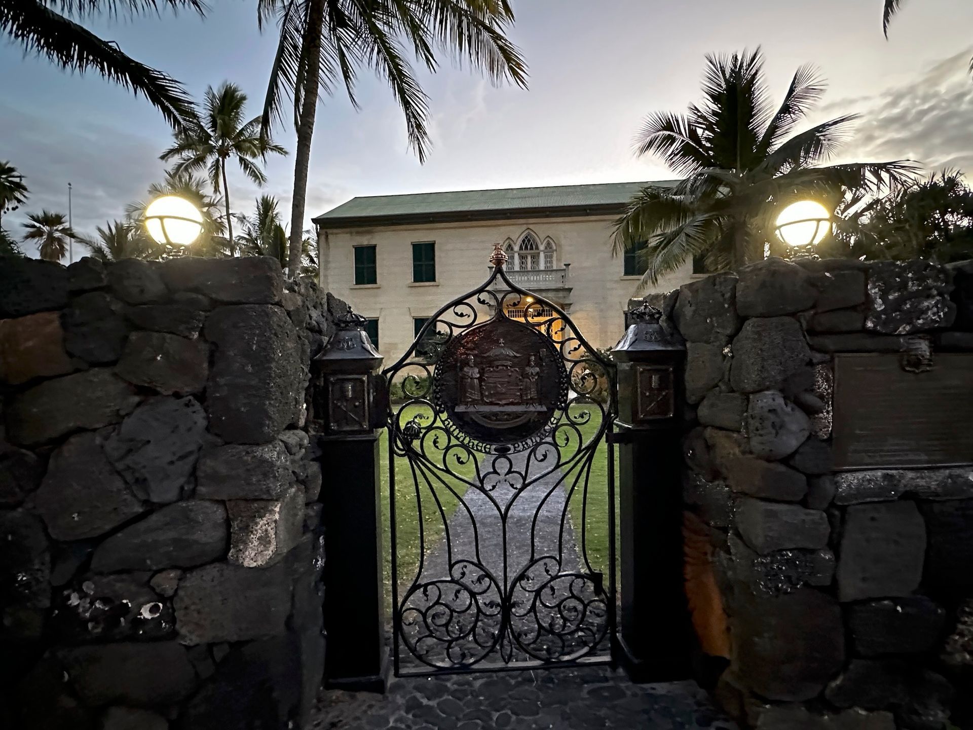 A stone wall with a wrought iron gate leading to a house