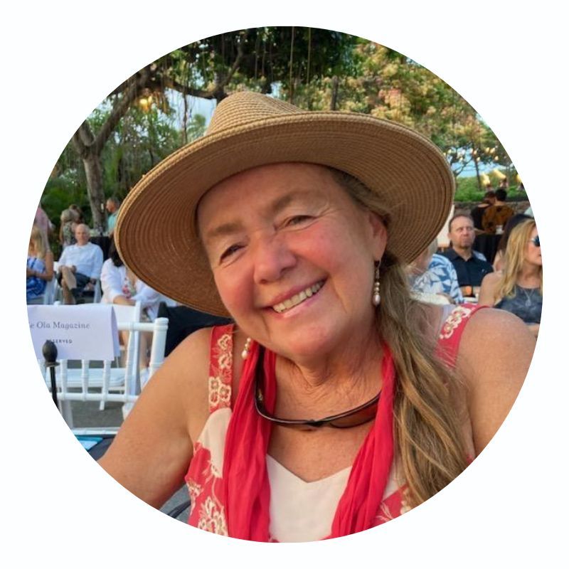 A woman wearing a hat and sunglasses is smiling for the camera.