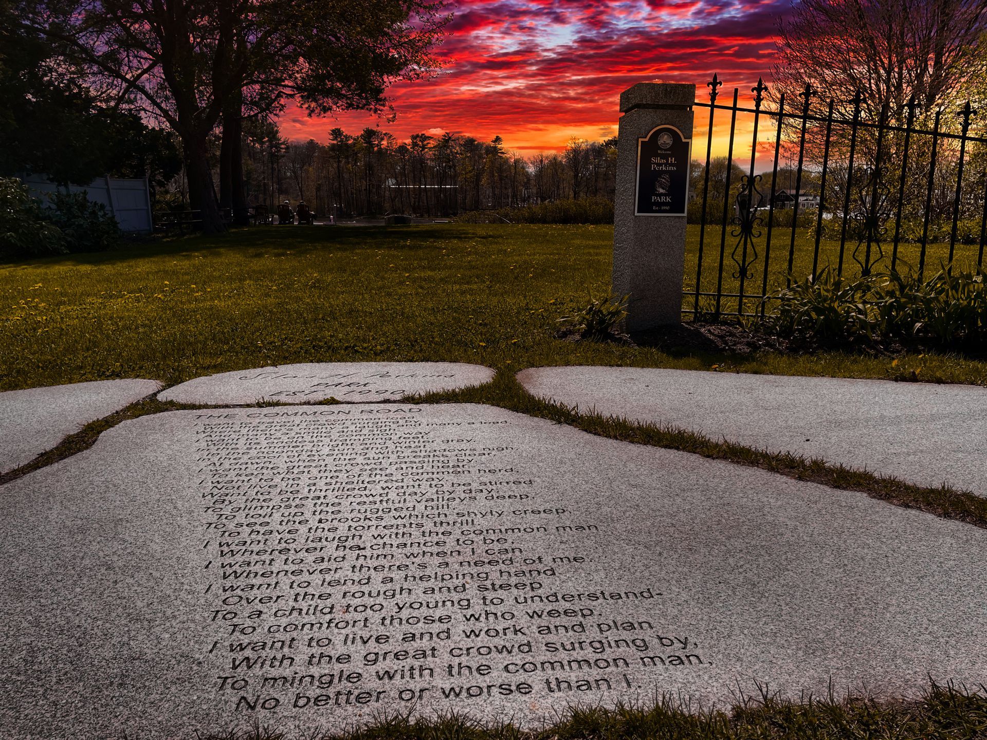 A gravestone in a park with a sunset in the background