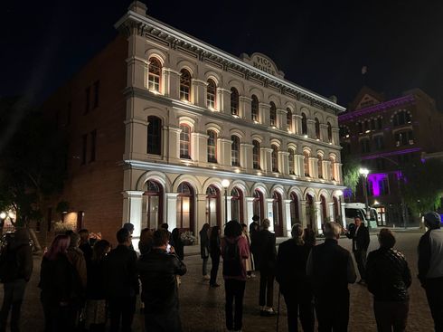 A group of people are standing in front of a large building at night