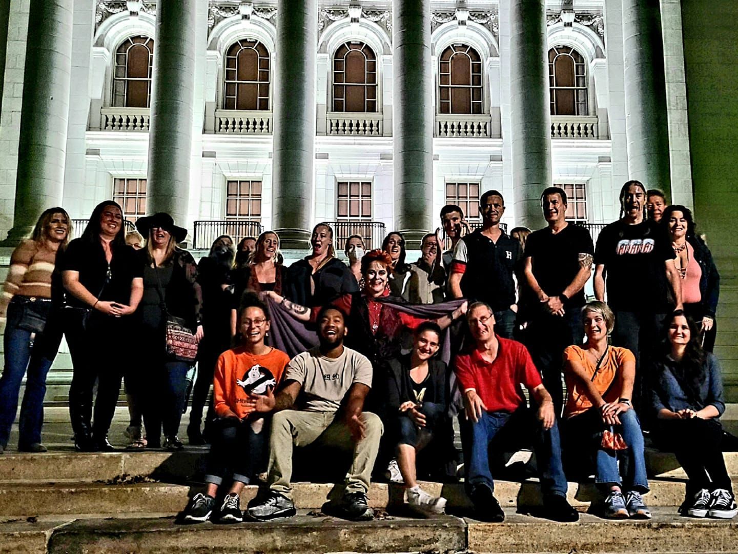 A group of people are posing for a picture in front of a building that says ' capitol ' on it