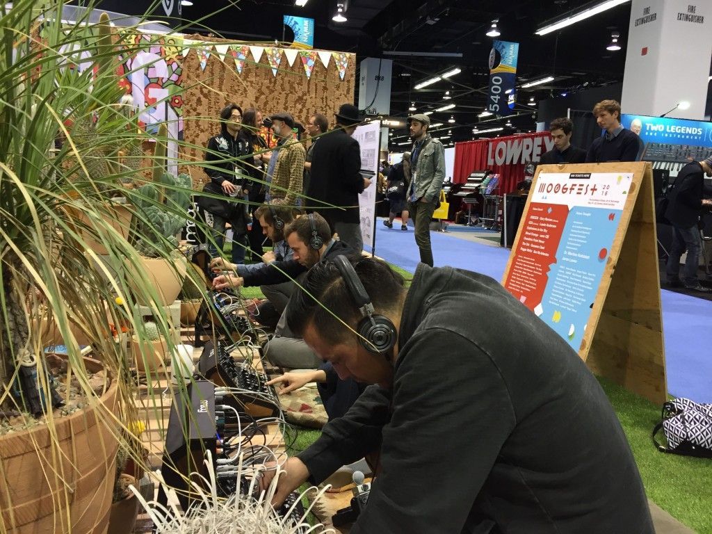 A man wearing headphones is working on a computer at a convention.