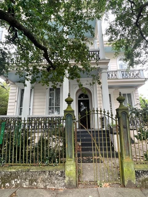 A large white house with a wrought iron fence around it